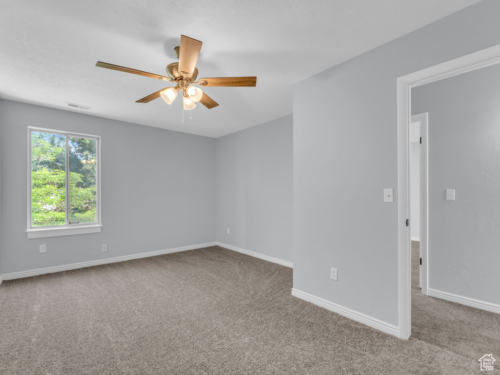 Carpeted empty room with a ceiling fan and baseboards