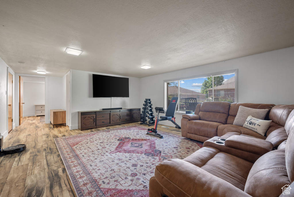 Living room with wood-type flooring, a textured ceiling, and baseboards