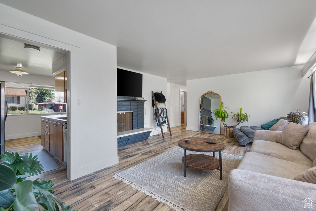 Living area with a brick fireplace, wood finished floors, and baseboards