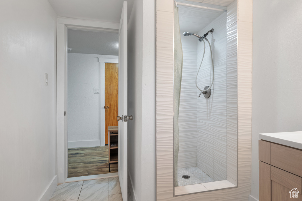 Bathroom with a stall shower, vanity, marble look tiles, and baseboards