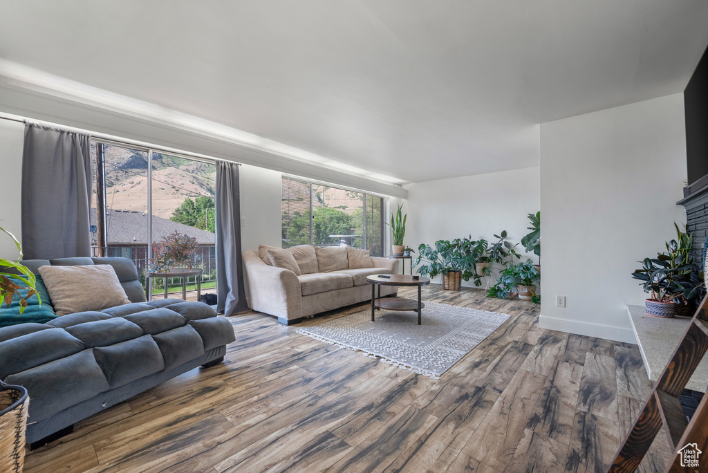 Living area with wood finished floors, a brick fireplace, and baseboards