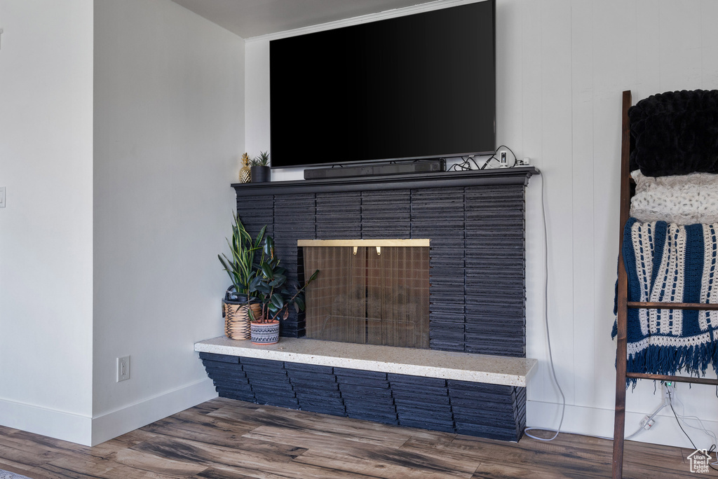 Detailed view of baseboards, wood finished floors, and a brick fireplace