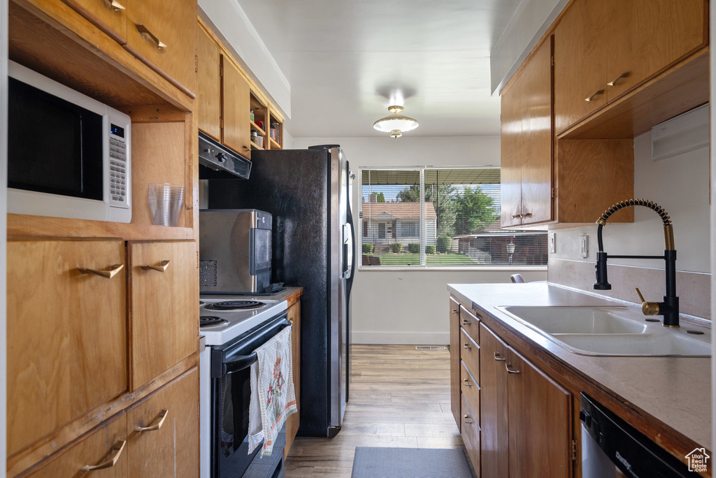 Kitchen featuring appliances with stainless steel finishes, a sink, light wood-style floors, and baseboards