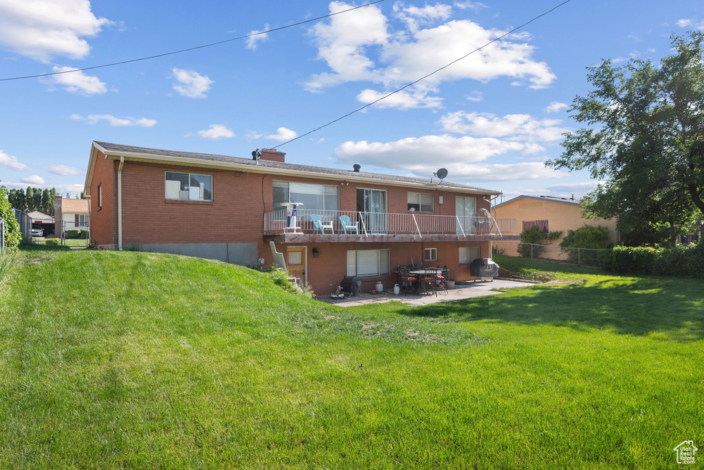Rear view of property featuring brick siding, a patio, and a wooden deck