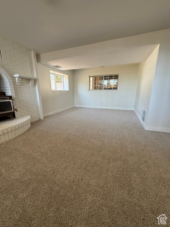 Unfurnished living room featuring a wood stove, baseboards, and carpet floors