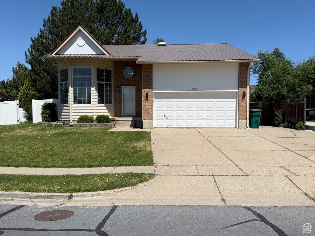 View of front of property with a garage, brick siding, concrete driveway, and metal roof
