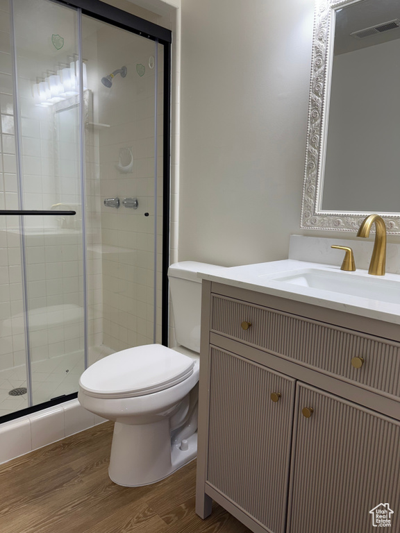 Bathroom with toilet, wood finished floors, a stall shower, and vanity