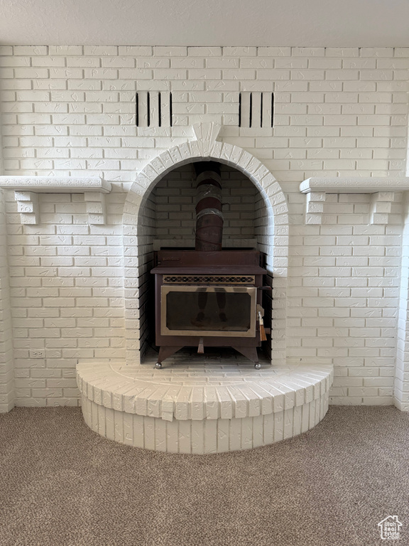 Detailed view of a wood stove, carpet, and brick wall