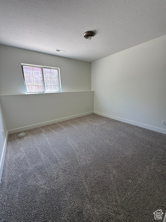 Unfurnished room featuring a textured ceiling, baseboards, and carpet
