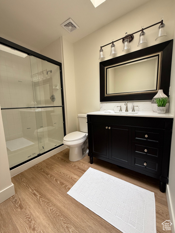 Full bathroom with wood finished floors, vanity, a shower stall, and toilet