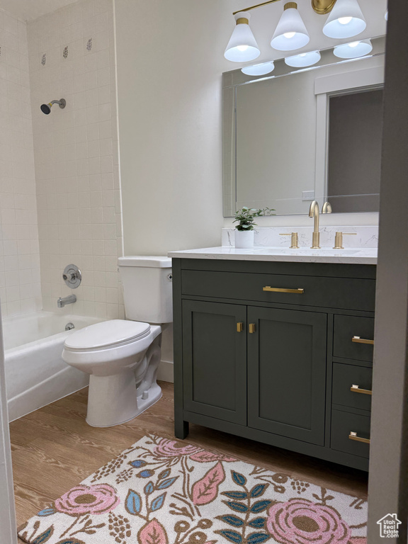 Full bath with wood finished floors, vanity, toilet, and shower / washtub combination