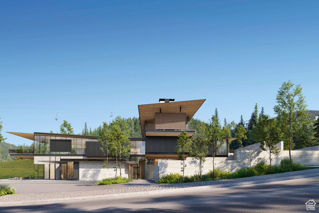 View of front of house featuring driveway, an attached garage, and a balcony