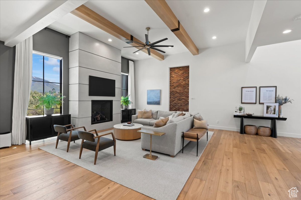 Living room with light wood finished floors, beamed ceiling, a ceiling fan, recessed lighting, and baseboards