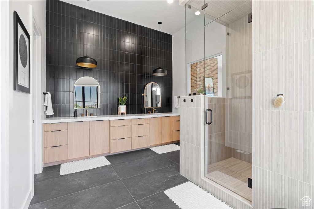Full bathroom with double vanity, a stall shower, tile walls, and tile patterned flooring