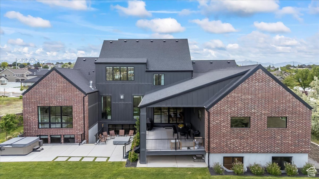 Back of property with a patio, a yard, brick siding, and roof with shingles