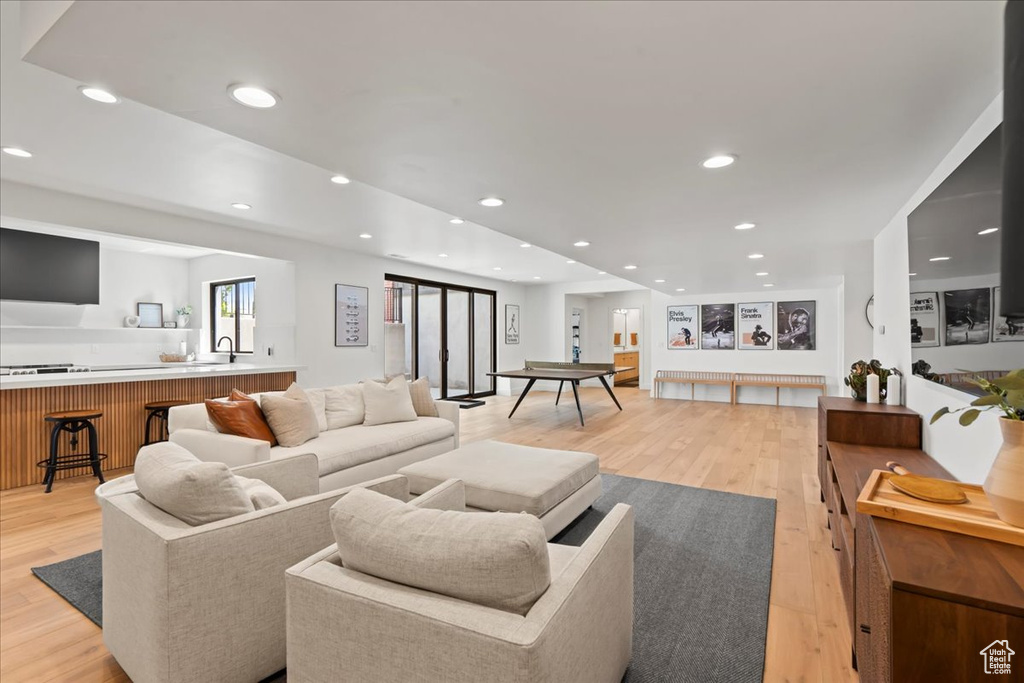 Living area with light wood finished floors and recessed lighting