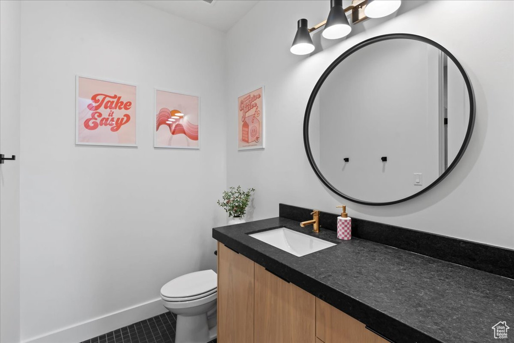 Bathroom featuring vanity, toilet, tile patterned flooring, and baseboards