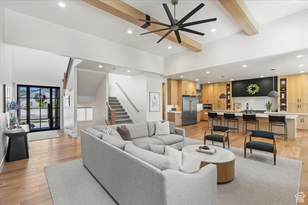 Living area featuring beam ceiling, ceiling fan, light wood-style floors, stairs, and recessed lighting