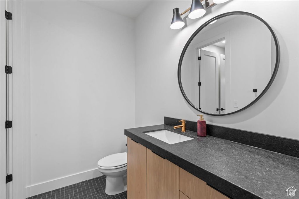 Bathroom with vanity, toilet, tile patterned flooring, and baseboards