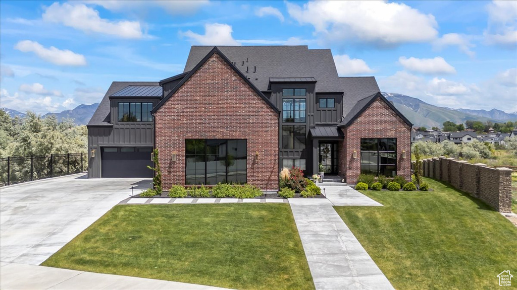 View of front of house featuring a standing seam roof, driveway, and a mountain view