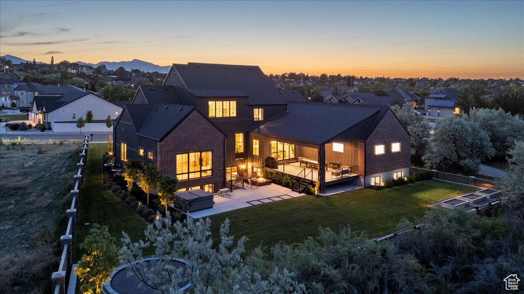 Back of property at dusk featuring a deck, a patio area, and a residential view