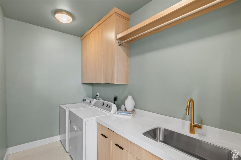 Washroom featuring cabinet space, washer and dryer, baseboards, and light tile patterned floors