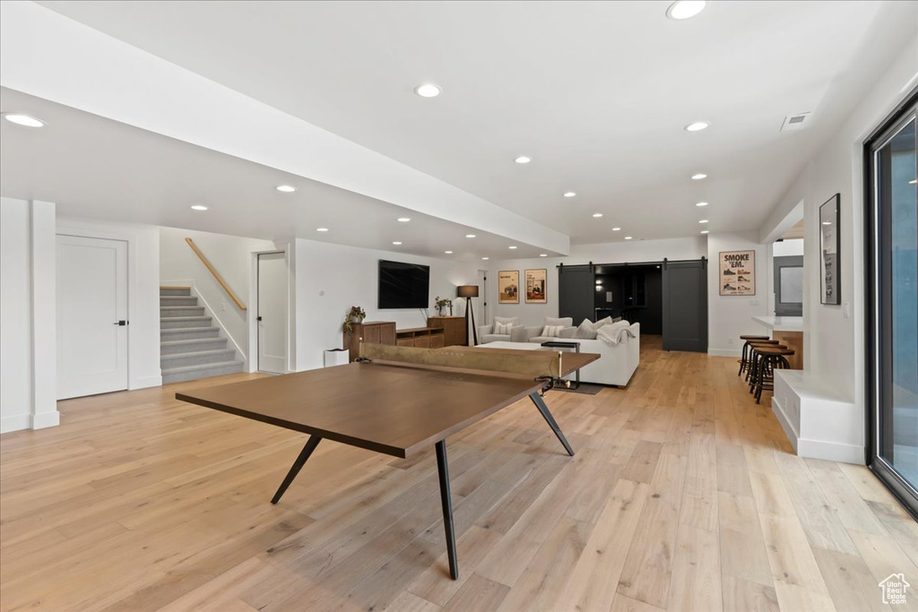 Playroom with light wood-style flooring, recessed lighting, and a barn door
