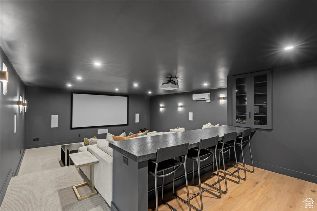 Cinema featuring a wall unit AC, recessed lighting, light wood-style flooring, and baseboards