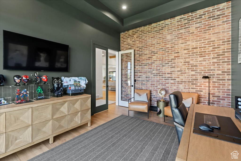 Office space featuring french doors, light wood-style flooring, and brick wall