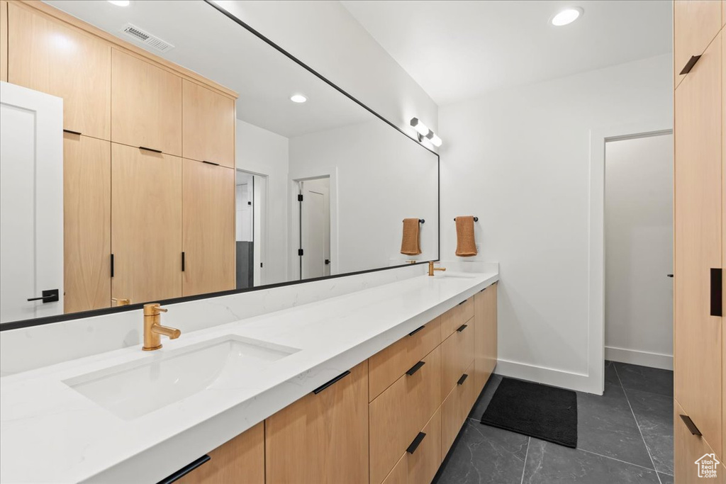Bathroom featuring double vanity, baseboards, recessed lighting, and tile patterned flooring