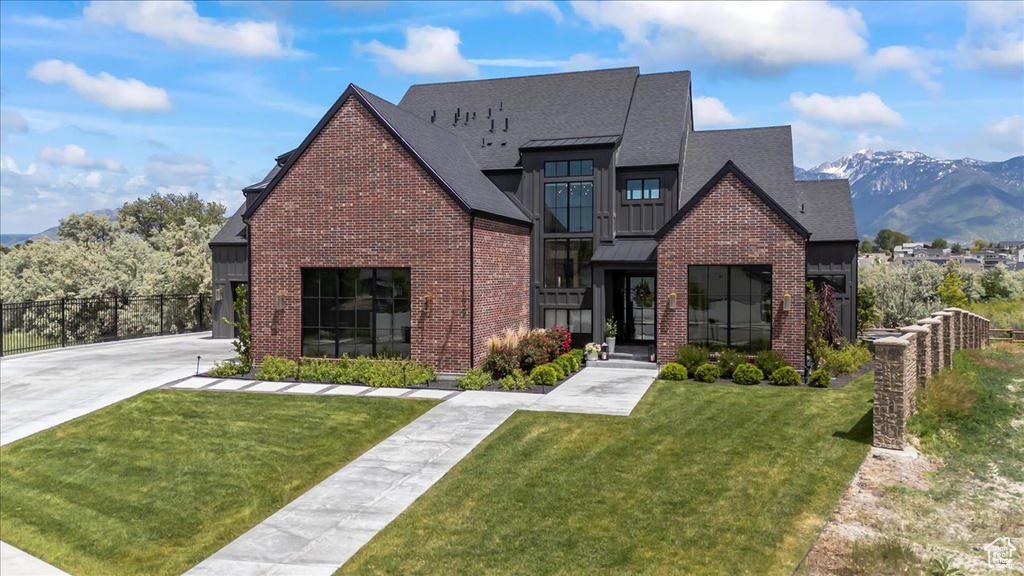 View of front facade featuring brick siding, a shingled roof, a mountain view, and board and batten siding