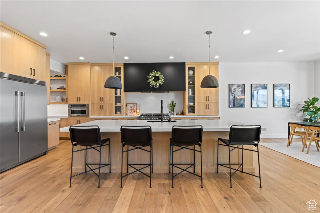 Kitchen with stainless steel appliances, light brown cabinetry, light countertops, recessed lighting, and a sink