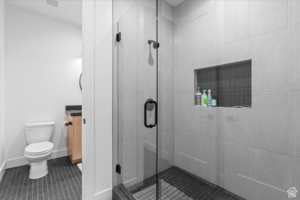 Full bath with toilet, a stall shower, tile patterned floors, and baseboards