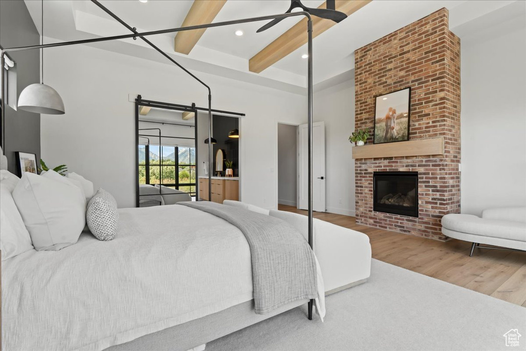 Bedroom featuring wood finished floors, beam ceiling, a brick fireplace, recessed lighting, and a towering ceiling