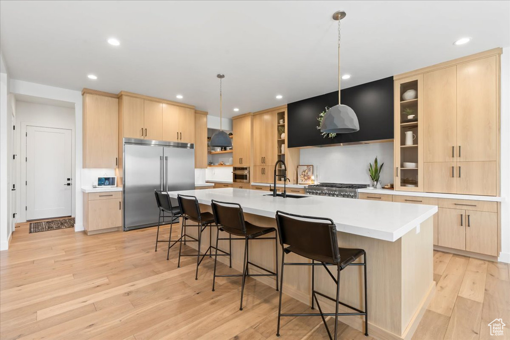 Kitchen with stainless steel appliances, light brown cabinets, light wood-style floors, recessed lighting, and a sink