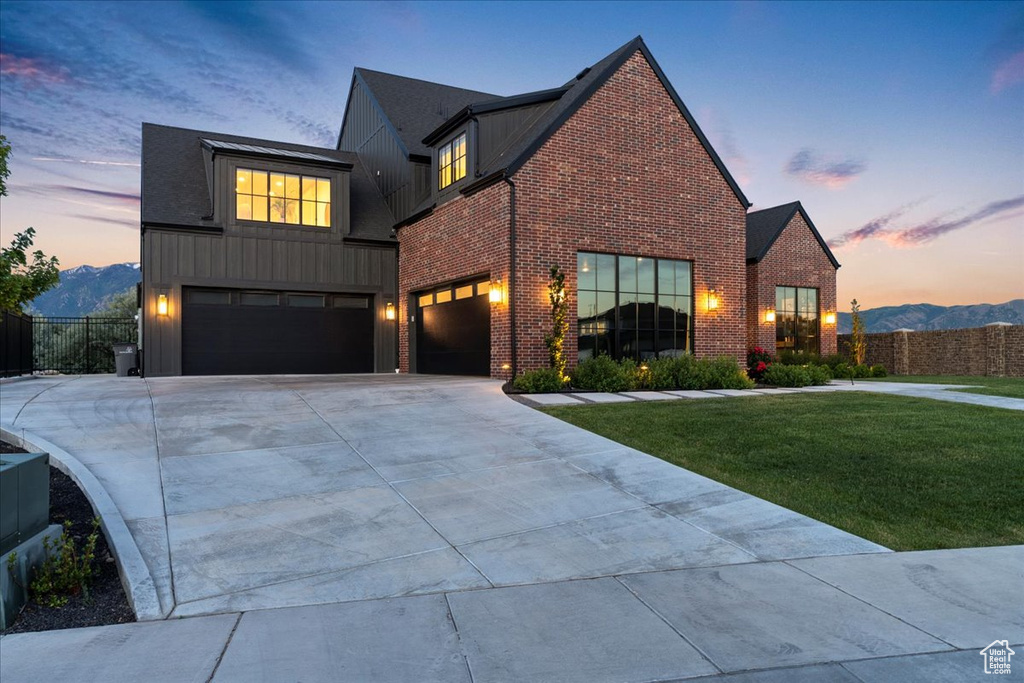 View of front of property with brick siding, driveway, an attached garage, board and batten siding, and a mountain view