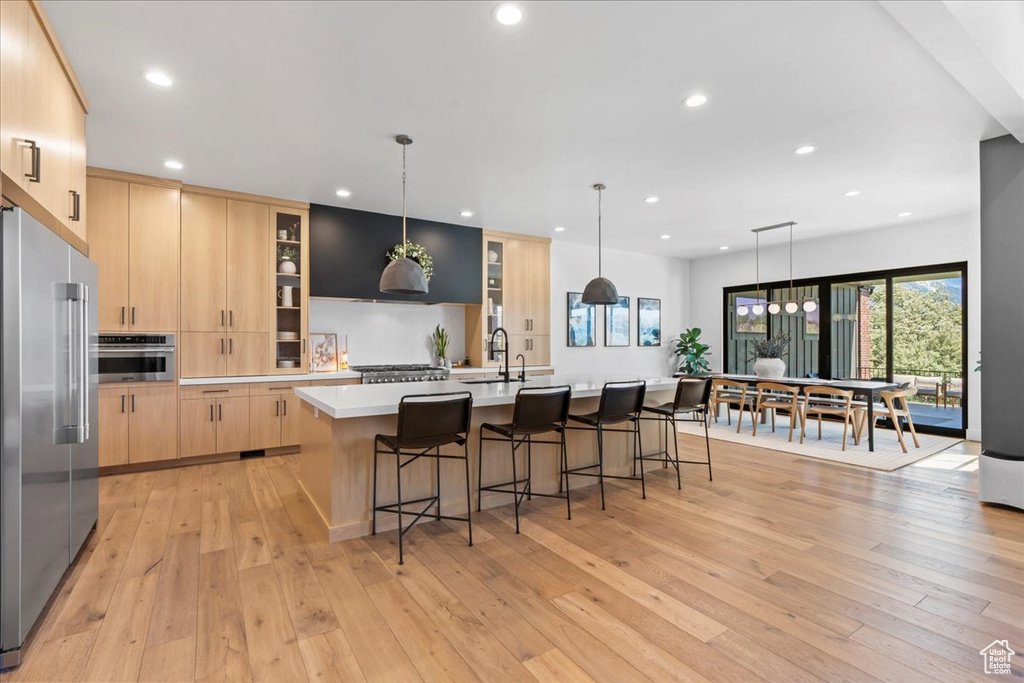 Kitchen featuring light brown cabinetry, stainless steel appliances, a sink, light wood-style flooring, and recessed lighting