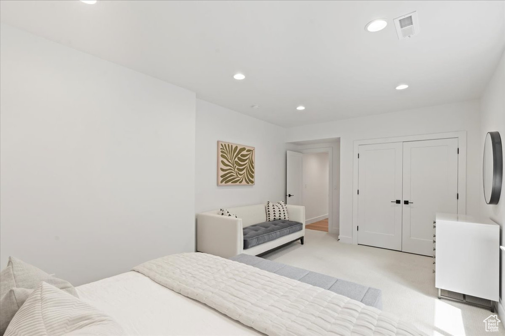 Bedroom with recessed lighting, light carpet, and a closet