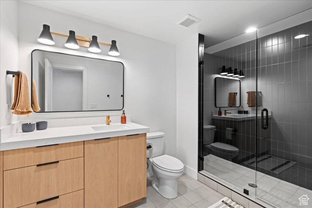 Bathroom with toilet, vanity, a shower stall, and tile patterned floors
