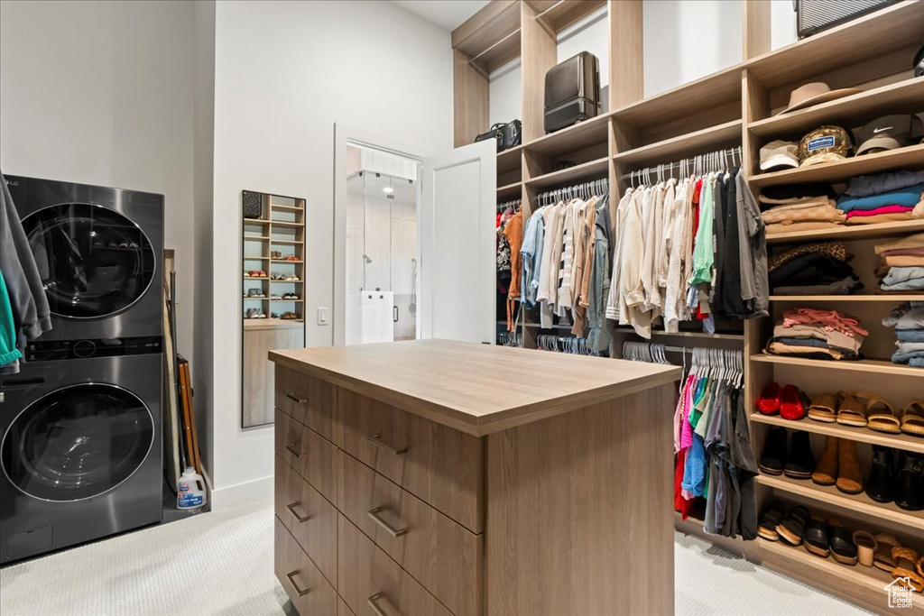 Walk in closet featuring stacked washer and clothes dryer and carpet flooring