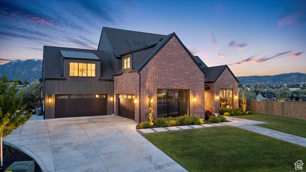 View of front of house featuring driveway, an attached garage, brick siding, and a mountain view