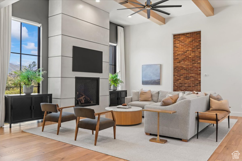 Living area with a ceiling fan, light wood-style floors, beam ceiling, a fireplace, and recessed lighting
