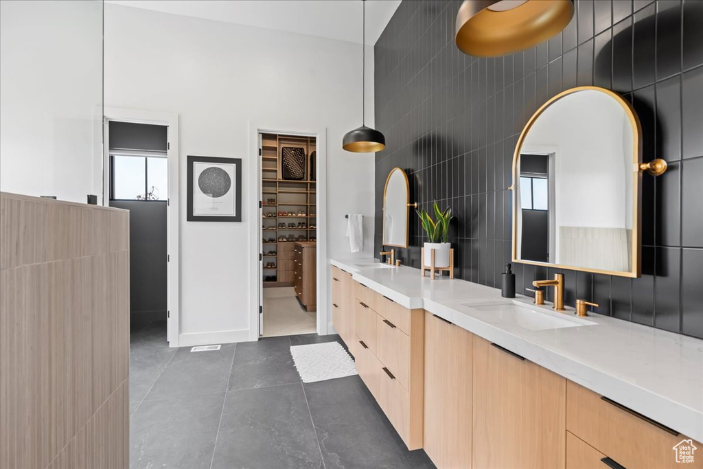 Bathroom featuring double vanity, tile patterned flooring, baseboards, and tile walls