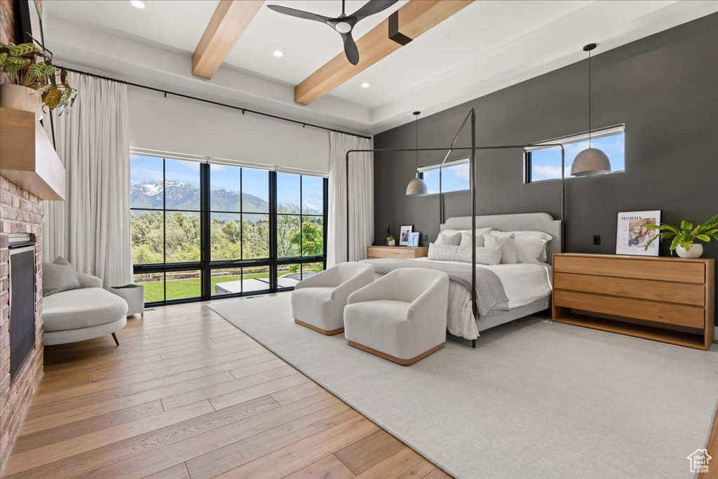 Bedroom with beam ceiling, a brick fireplace, a mountain view, a towering ceiling, and wood finished floors