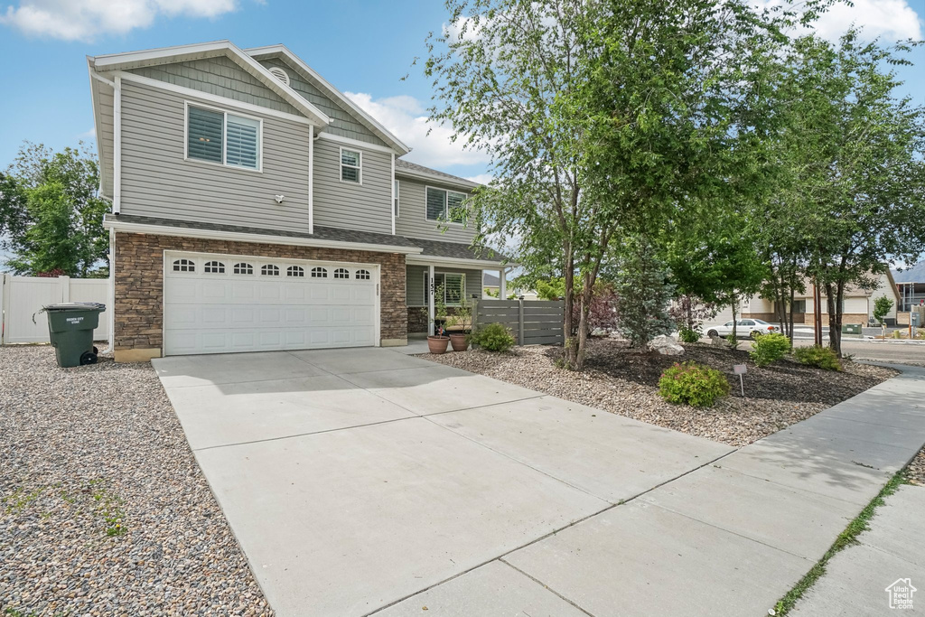 View of front of home featuring a garage, concrete driveway, and stone siding