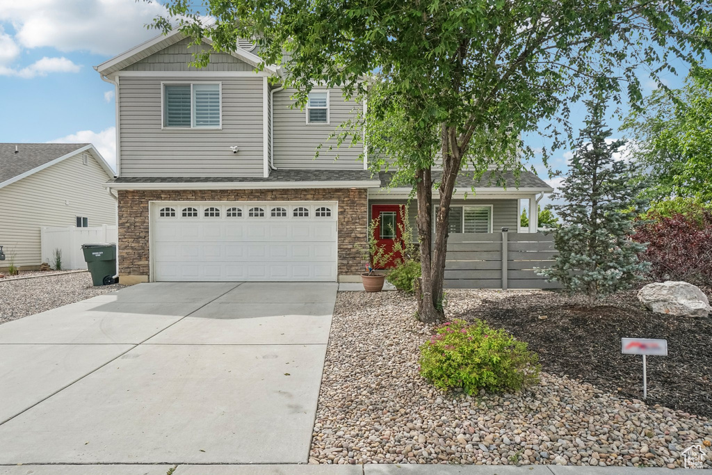 View of front of home featuring concrete driveway, a garage, and stone siding