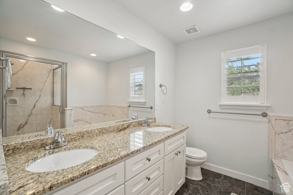 Full bath featuring plenty of natural light, double vanity, a marble finish shower, toilet, and recessed lighting
