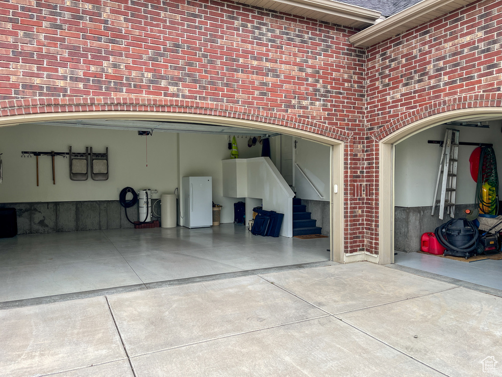 Garage featuring freestanding refrigerator and driveway