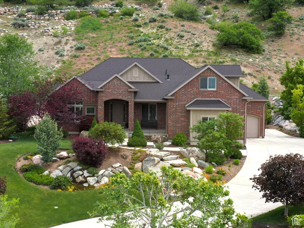 View of front of home featuring driveway, brick siding, a front lawn, and an attached garage