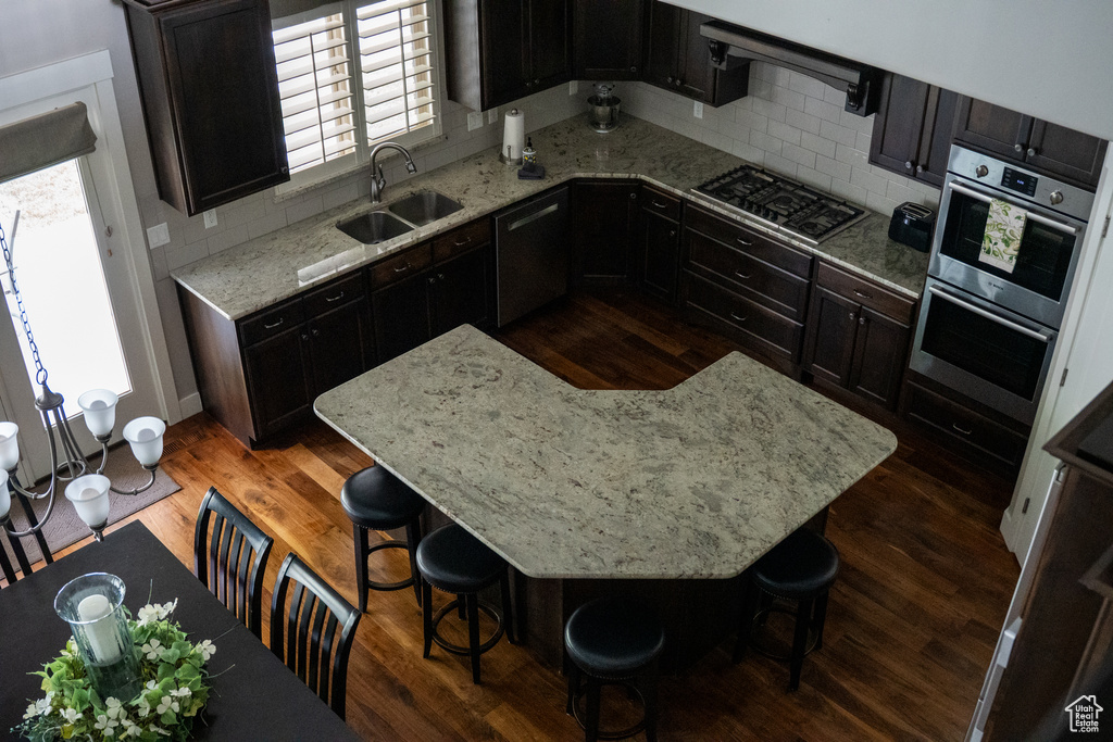 Kitchen with stainless steel appliances, a sink, backsplash, and dark wood-style flooring